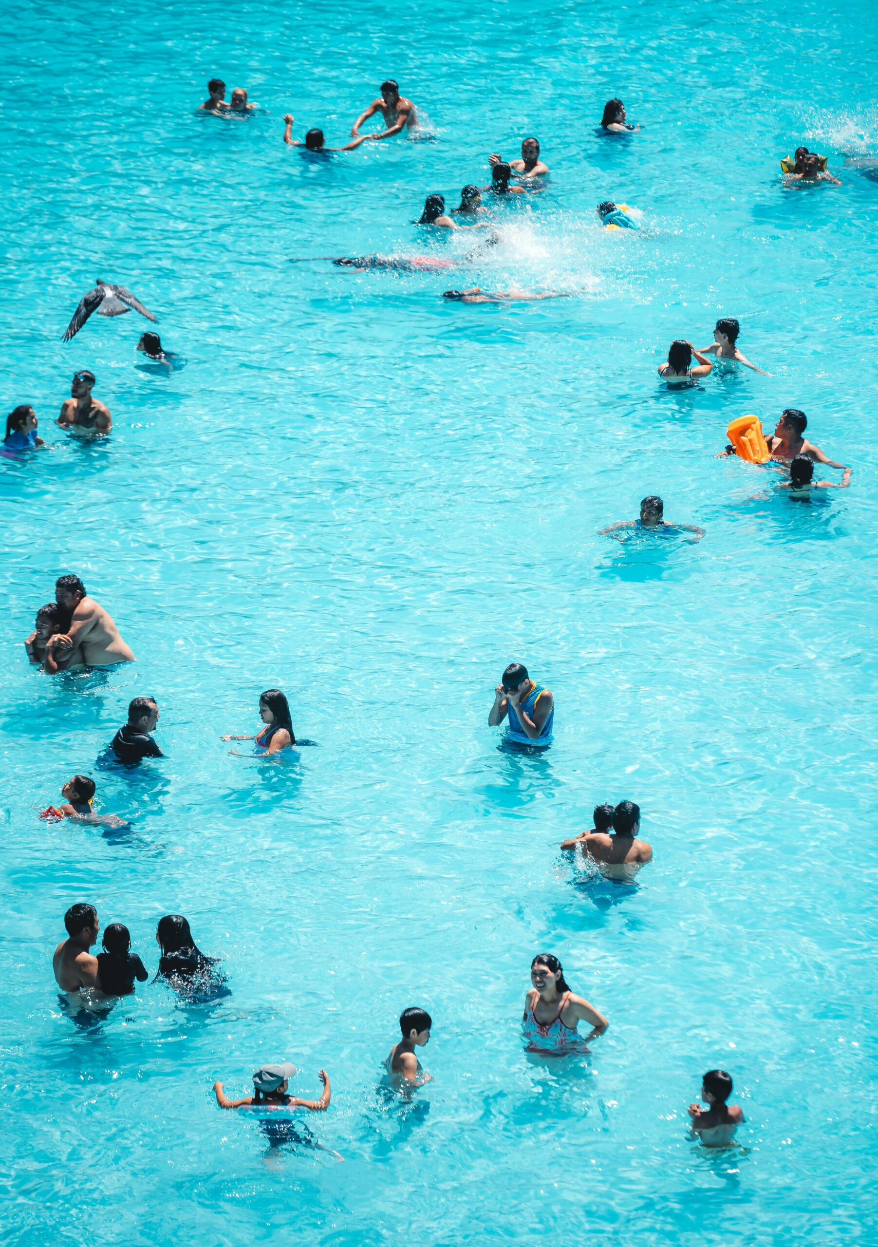 Crowded pool, people swimming and splashing in the water